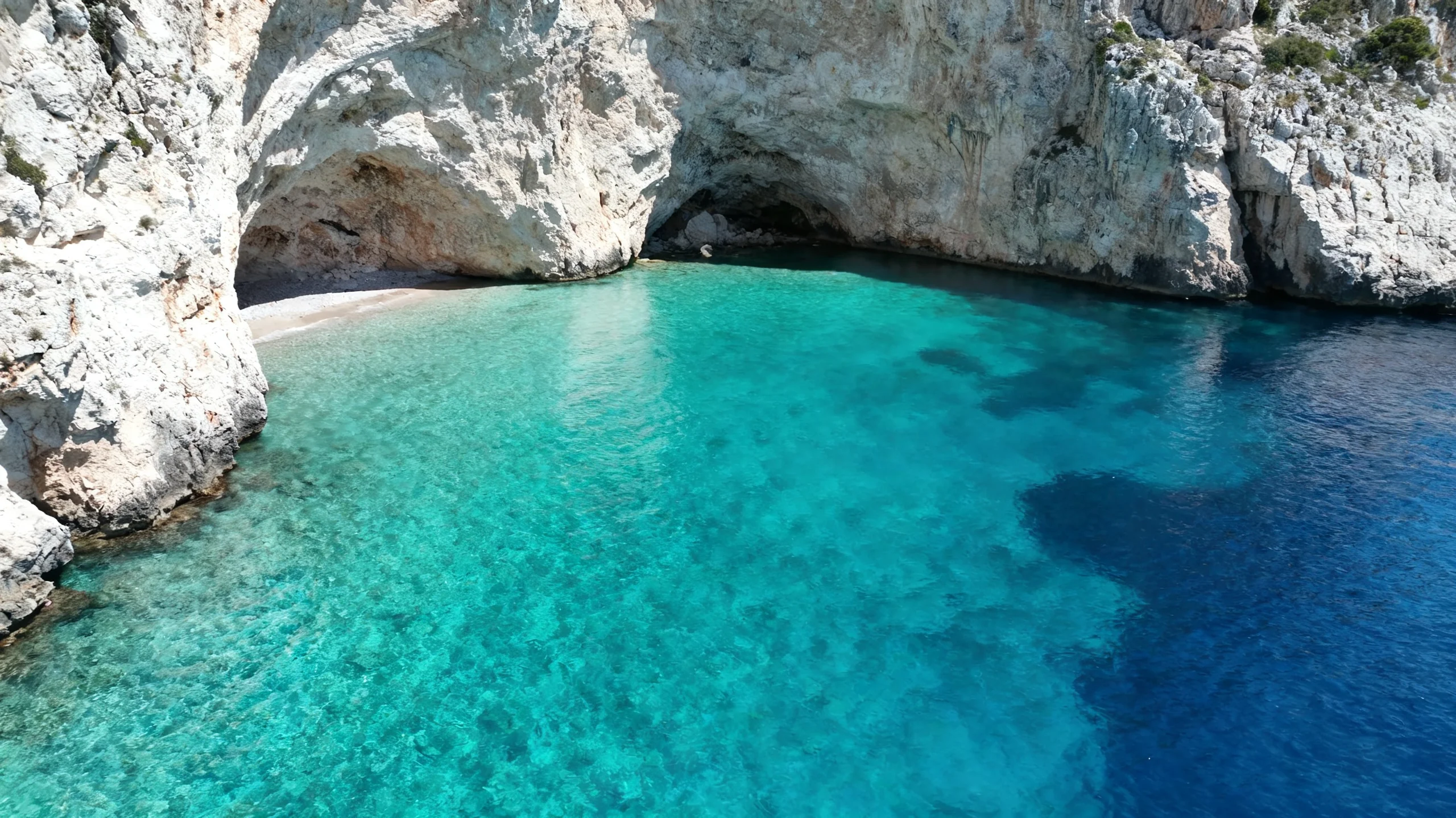 The Crystal Lagoon on Comino's western side, empty turquoise water, with limestone cliffs framing the cove