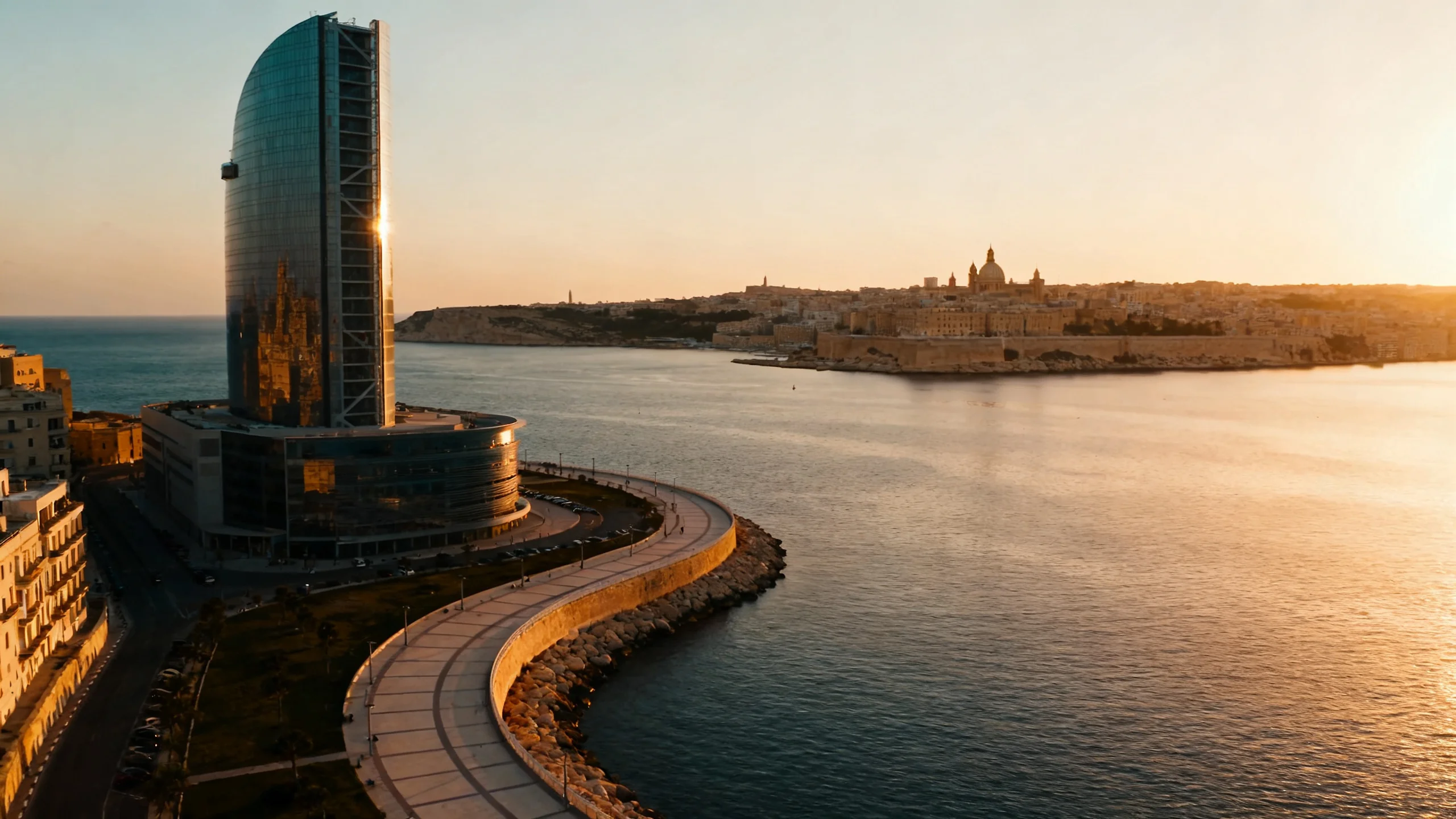 De Sliema Strand-kustlijn tijdens het gouden uur, met de Tigne Point-toren op de achtergrond